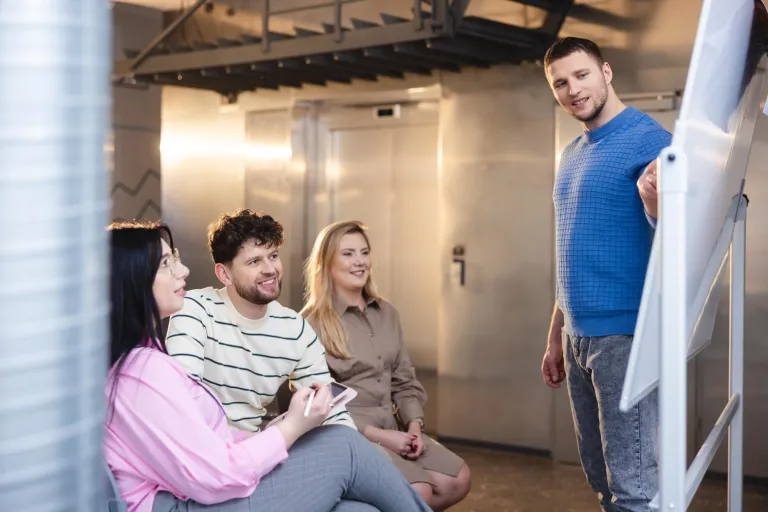 Wyniki wyszukiwania | Uniwersytet WSB Merito Łódź: Student prezentuje na tablicy, a trójka słucha.