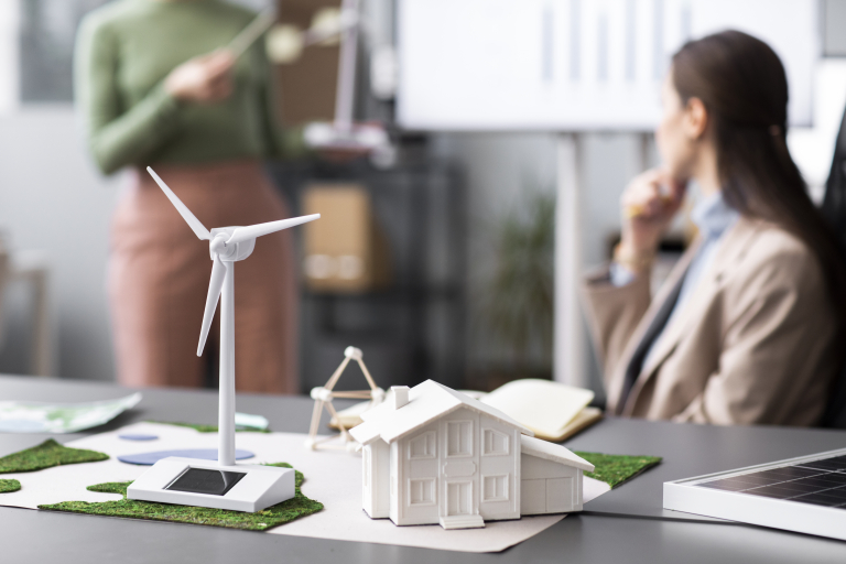 Efektywność energetyczna, odnawialne źródła energii i inne narzędzia prowadzące do transformacji energetycznej | Studia podyplomowe w Opolu | Uniwersytet WSB Merito Opole: Model turbiny wiatrowej z osobami w tle