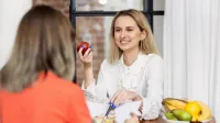 Dietetyka | Studia I stopnia w Opolu | Uniwersytet WSB Merito Opole: Główna grafika: Opole - dietetyka - dwie dziewczyny patrzące na siebie, dziewczyna w białej bluzce trzyma w dłoni jabłko