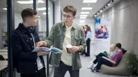 Bezpieczeństwo i higiena pracy | Studia I stopnia w Opolu | Uniwersytet WSB Merito Opole: Główna grafika: Opole - Bezpieczeństwo i higiena pracy  - studenci stojący na korytarzu, przeglądają notatki