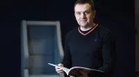 Marketing cyfrowy i grafika reklamowa | Studia I stopnia w Opolu | Uniwersytet WSB Merito Opole: Główna grafika: Opole - specjalność Marketing cyfrowy i grafika reklamowa - mężczyzna w średnim wieku z książką w dłoni