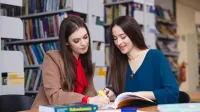 Zarządzanie kryzysowe i pomoc humanitarna | Studia II stopnia w Opolu | Uniwersytet WSB Merito Opole: Główna grafika: Opole - specjalność Administracja bezpieczeństwa publicznego - studentki w bibliotece