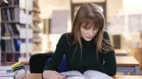 Pedagogika | Studia II stopnia w Opolu | Uniwersytet WSB Merito Opole: Kobieta w ciemnym swetrze czyta książkę w bibliotece