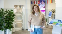 Seksuologia | Studia podyplomowe w Opolu | Uniwersytet WSB Merito Opole: Główna grafika: Opole - studia podyplomowe - Seksuologia - Kobieta trzymająca w dłoni książkę, stoi na korytarzu