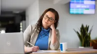 Zarządzanie jakością w branży automotive | Studia podyplomowe w Opolu | Uniwersytet WSB Merito Opole: Główna grafika: Opole - studia podyplomowe - Zarządzanie jakością w branży automotive - Kobieta siedząca przy biurku, pisze w notatniku