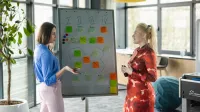 Efektywność energetyczna, odnawialne źródła energii i inne narzędzia prowadzące do transformacji energetycznej | Studia podyplomowe w Opolu | Uniwersytet WSB Merito Opole: Główna grafika: Opole - studia podyplomowe - Efektywność energetyczna, odnawialne   źródła energii i inne narzędzia prowadzące do transformacji energetycznej - dwie kobiety stojące przy tablicy, na której widać notatki i wykresy