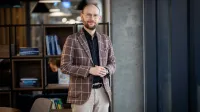 Zarządzanie jakością w branży automotive | Studia podyplomowe w Opolu | Uniwersytet WSB Merito Opole: Główna grafika: Opole - studia podyplomowe - Zarządzanie jakością w branży automotive - Mężczyzna stojący w kawiarni