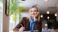 Zarządzanie i automatyzacja procesów w administracji publicznej | Studia podyplomowe w Opolu | Uniwersytet WSB Merito Opole: Główna grafika: Opole - studia podyplomowe - Zarządzanie i automatyzacja procesów w administracji publicznej - Kobieta siedząca w kawiarni, tworzy notatki, przed nią leża markery i książki