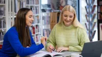 Audyt wewnętrzny i controlling | Studia podyplomowe w Opolu | Uniwersytet WSB Merito Opole: Główna grafika: Opole - studia podyplomowe - Audyt wewnętrzny i controlling - Dwie kobiety wspólnie robiące notatki