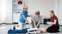 Zarządzanie kryzysowe i pomoc humanitarna | Studia II stopnia ze studiami podyplomowymi  | Uniwersytet WSB Merito Opole: Główna grafika: Opole - Studia II stopnia z podyplomowymi - specjalność Zarządzanie kryzysowe i pomoc humanitarna - Wykładowczyni pokazująca jak wykonywać pierwszą pomoc