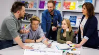 Doradztwo podatkowe | Studia II stopnia ze studiami podyplomowymi  | Uniwersytet WSB Merito Opole: Główna grafika: Opole - studia II stopnia z podyplomowymi - specjalność Doradztwo podatkowe - Grupa osób w bibliotece wspólnie tworząca projekt
