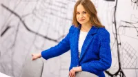 Doradztwo podatkowe | Studia II stopnia w Opolu | Uniwersytet WSB Merito Opole: Główna grafika: Opole - studia II stopnia - specjalność Doradztwo podatkowe - Kobieta w niebieskiej marynarce, stoi za stołem konferencyjnym