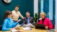 Rachunkowość i sprawozdawczość finansowa | Studia II stopnia w Opolu | Uniwersytet WSB Merito Opole: Główna grafika: Opole - studia II stopnia - specjalność Rachunkowość i sprawozdawczość finansowa - Grupa rozmawiających osób, na stole przed nimi leżą notatki