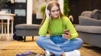 Pedagogika resocjalizacyjna z socjoterapią i kryminologią | Studia II stopnia w Opolu | Uniwersytet WSB Merito Opole: Główna grafika: Opole - studia II stopnia - specjalność Pedagogika resocjalizacyjna z socjoterapią - Dziewczyna siedząca na podłodze, słucha muzyki
