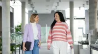 Kompetencje przyszłości - przewaga w świecie zmian | Studia podyplomowe w Opolu | Uniwersytet WSB Merito Opole: Główna grafika: Opole- studia podyplomowe- Kompetencje Przyszłości - Przewaga w Świecie Zmian- uczestniczki studiów podyplomowych rozmawiają, idąc koryatrzem