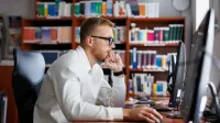 Informatyka | Studia I stopnia w Opolu | Uniwersytet WSB Merito Opole: Główna grafika: Opole - studia I stopnia inżynierskie- Informatyka - student siedzi przy biurku przy komputerze