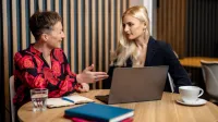 Interwencja kryzysowa | Studia podyplomowe w Opolu | Uniwersytet WSB Merito Opole: Główna grafika: Opole - studia podyplomowe - Interwencja Kryzysowa - uczestniczki studiów podyplomowych siedzą przy stoliku z laptopem i rozmawiają