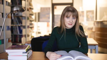 Prawo w finansach | Studia I stopnia w Opolu | Uniwersytet WSB Merito Opole: Główna grafika: Opole - specjalność mediacje i negocjacje - studentka siedząca przed książką