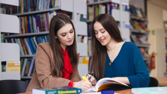 Zarządzanie kryzysowe i pomoc humanitarna | Studia II stopnia w Opolu | Uniwersytet WSB Merito Opole: Główna grafika: Opole - specjalność Administracja bezpieczeństwa publicznego - studentki w bibliotece