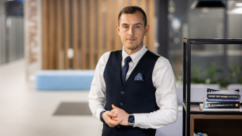Pentester - specjalista ds. cyberbezpieczeństwa | Studia podyplomowe w Opolu | Uniwersytet WSB Merito Opole: Pentester - specjalista ds. cyberbezpieczeństwa - mężczyzna  w kawiarni, stoi obok regału na książki