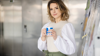 Psychodietetyka | Studia I stopnia w Opolu | Uniwersytet WSB Merito Opole: Główna grafika: Opole - studia I stopnia - specjalność psychodietetyka - Kobieta trzymająca kubek z logotypem Uniwersytetu WSB Merito