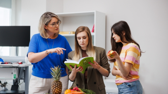 Psychodietetyka i terapia zaburzeń odżywiania | Studia II stopnia w Opolu | Uniwersytet WSB Merito Opole: Główna grafika: Opole - studia II stopnia- Dietetyka: Psychodietetyka i terapia zaburzeń odżywiania- studentki analizują książkę w laboratorium dietetycznym