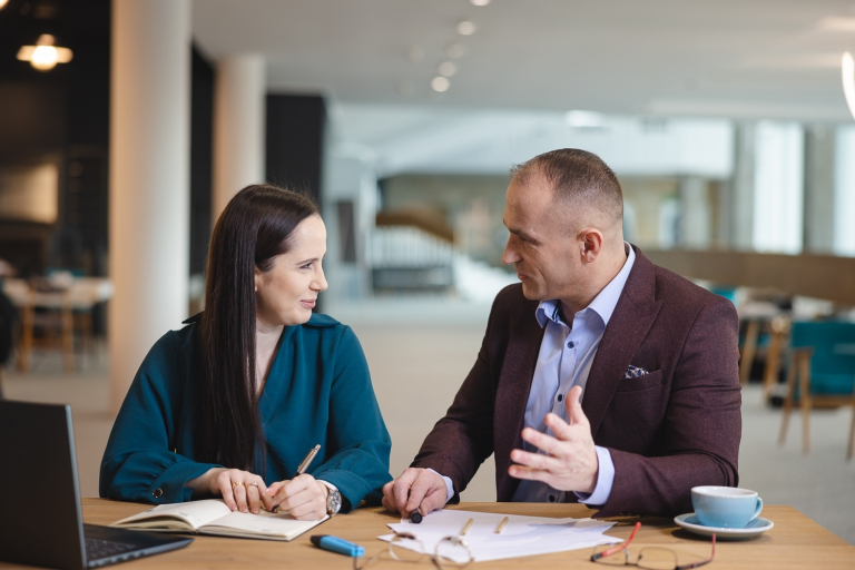 Administracja – prawo, zarządzanie i organizacja | Studia podyplomowe w Opolu | Uniwersytet WSB Merito Opole: Dwie osoby rozmawiające przy kawie, przeglądają notatki