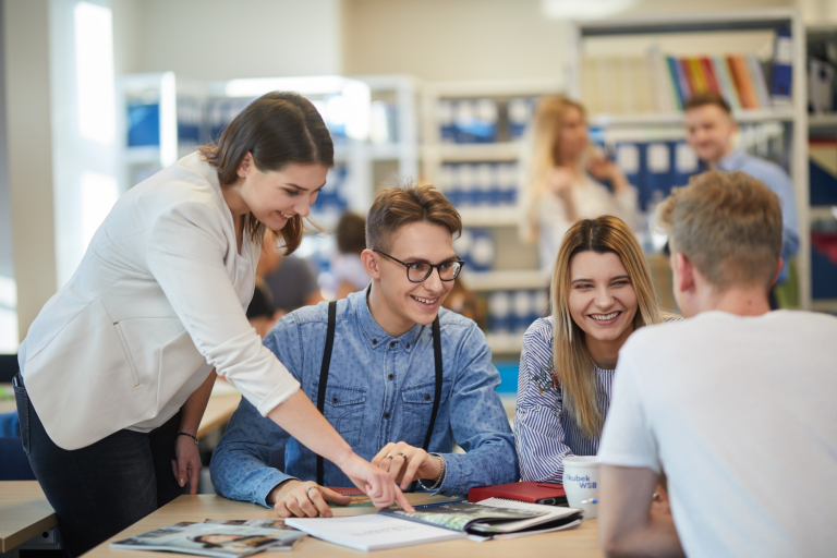 Doradztwo podatkowe | Studia II stopnia ze studiami podyplomowymi  | Uniwersytet WSB Merito Opole: Grupa osób w bibliotece, przeglądają notatki