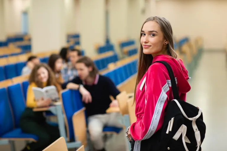 Pedagogika opiekuńczo-wychowawcza z neuropedagogiką | Studia I stopnia w Opolu | Uniwersytet WSB Merito Opole: Młoda dziewczyna patrzy w obiektyw a tle widać grupę dziewcząt