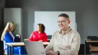 Bibliotekoznawstwo | Studia podyplomowe w Poznaniu | Uniwersytet WSB Merito w Poznaniu: Mężczyzna przy laptopie w sali wykładowej.
