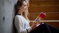 Zarządzanie gospodarką komunalną | Studia II stopnia ze studiami podyplomowymi  | Uniwersytet WSB Merito w Poznaniu: Studentka siedzi na schodach, oparta o betonową ścianę