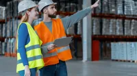 Logistyka | Studia I stopnia w Poznaniu | Uniwersytet WSB Merito w Poznaniu: kobieta i mężczyzna w kamilelkach odblaskowych i kaskach ochronnych