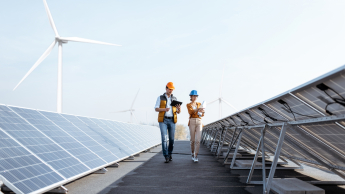 Efektywność energetyczna, odnawialne źródła energii i inne narzędzia prowadzące do transformacji energetycznej | Studia podyplomowe w Poznaniu | Uniwersytet WSB Merito w Poznaniu: dwie osoby idę pomiędzy panelami słonecznymi
