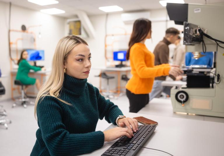Stypendia i zniżki | Uniwersytet WSB Merito w Poznaniu: Studentka pracuje przy komputerze w nowoczesnym laboratorium