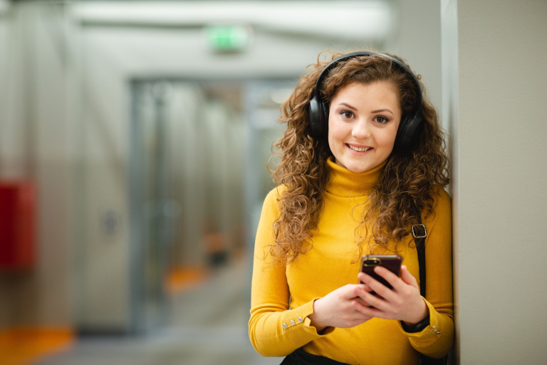 Samorząd studencki | Uniwersytet WSB Merito w Poznaniu: Studentka WSB Merito Poznań słucha muzyki na korytarzu uczelni