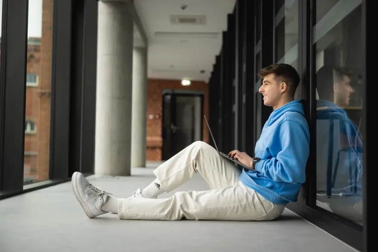 Virtual Reality and Multimedia | Studia I stopnia w Poznaniu | Uniwersytet WSB Merito w Poznaniu: Poznań - student w korytarzu z laptopem