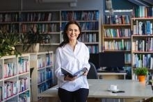 Uczestniczka MB Atoruń stoi na korytarzu z książką- Uniwersytety WSB Merito