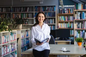 Studia MBA i EMBA | Uniwersytet WSB Merito: Uczestniczka MBA pozuje z informatorem w bibliotece- Uniwersytet WSB Merito Toruń