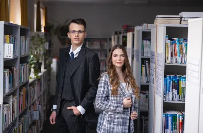 Poradniki - dzielimy się wiedzą | Uniwersytet WSB Merito: Główna grafika: Dwie osoby w blibliotece
