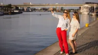 Hotelarstwo i gastronomia | Studia I stopnia w Szczecinie | Uniwersytet WSB Merito Szczecin: Dwie studentki Uniwersytetu WSB Merito Szczecin robią selfie nad Odrą w słoneczny dzień.