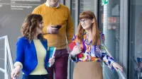 Zarządzanie jakością i produkcją w branży produkcyjnej | Studia podyplomowe w Szczecinie | Uniwersytet WSB Merito Szczecin: Trzy osoby schodzą po schodach, prowadząc rozmowę.
