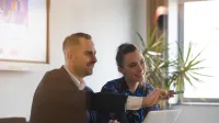 Zarządzanie i marketing | Studia II stopnia w Szczecinie | Uniwersytet WSB Merito Szczecin: Dwie osoby pracują przy laptopie, omawiając prezentację.