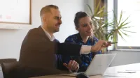 Polityka wynagrodzeń i wartościowanie stanowisk w świetle nowych regulacji UE | Studia podyplomowe w Szczecinie | Uniwersytet WSB Merito Szczecin: Dwie osoby pracują przy laptopie, omawiając prezentację.