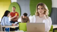 Psychologia rozwoju osobistego | Studia I stopnia w Szczecinie | Uniwersytet WSB Merito Szczecin: Studentka pracuje przy laptopie w nowoczesnej strefie wspólnej, w tle inni studenci.