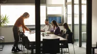 Tester Automatyzujący | Uniwersytet WSB Merito Szczecin: Cztery osoby pracują wspólnie przy stole w sali konferencyjnej.