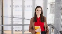 Copywriting sprzedażowy z AI | Uniwersytet WSB Merito Szczecin: Uśmiechnięta studentka w budynku uczelni trzyma książkę