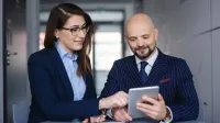 Nowoczesne przywództwo w biznesie | Studia podyplomowe w Szczecinie | Uniwersytet WSB Merito Szczecin: uczestnicy MBA rozmawiają przy stole i tablecie