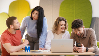 Programista Python Developer | Studia podyplomowe w Szczecinie | Uniwersytet WSB Merito Szczecin: grupa studentów w kolorowej sali pracuje przy laptopie
