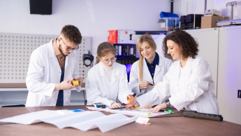Zarządzanie produkcją | Studia podyplomowe w Szczecinie | Uniwersytet WSB Merito Szczecin: Grupa studentów w fartuchach w sali laboratoryjnej