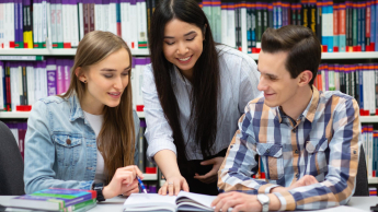 Psychoneuroimmunologia (PNI) | Studia podyplomowe w Szczecinie | Uniwersytet WSB Merito Szczecin: Studenci uczą się razem przy stole w bibliotece.